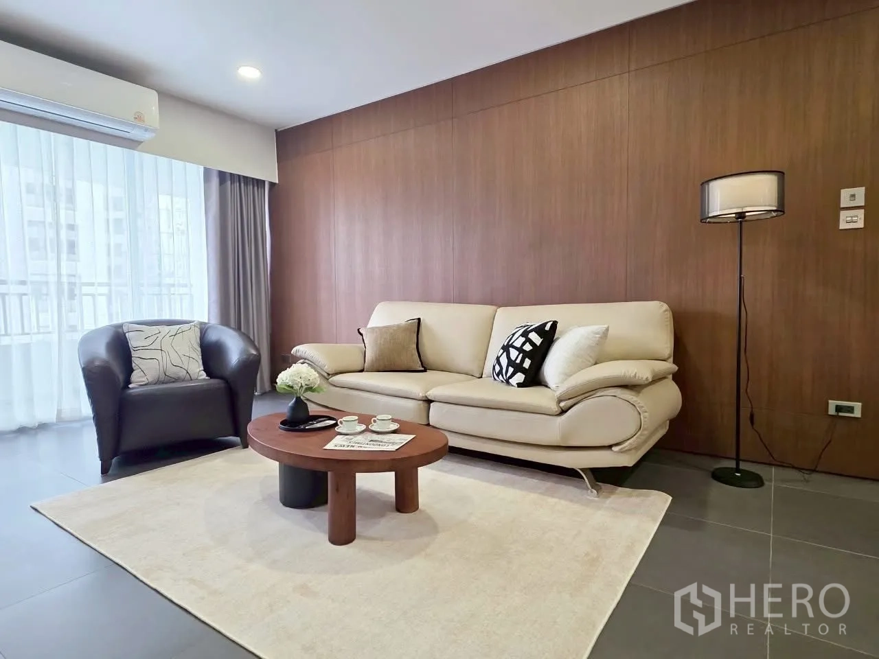 Condominium for rent in Sathon, Bangkok - Seating corner with cream sofa, round coffee table and floor lamp.