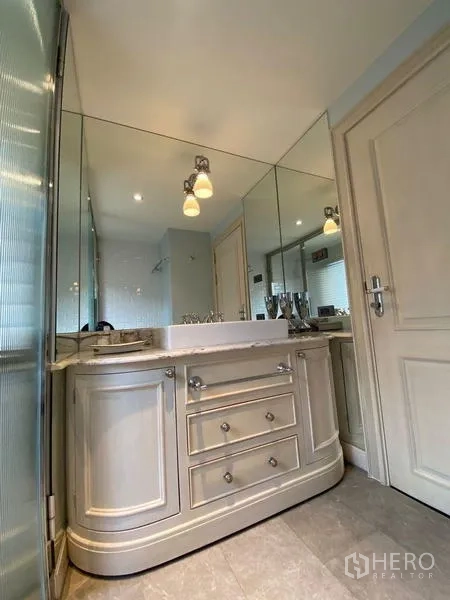 Condominium for rent in Khlong San, Bangkok - Bathroom featuring a large mirrored vanity with classic cabinetry and soft lighting.