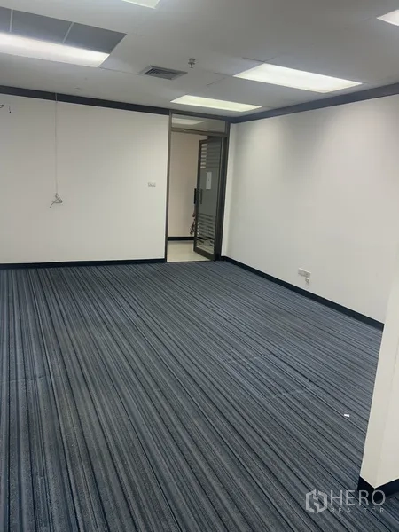 办公空间 出租在Pathum Wan, Bangkok - 明亮的办公区，条纹地毯、白墙与玻璃入口门。