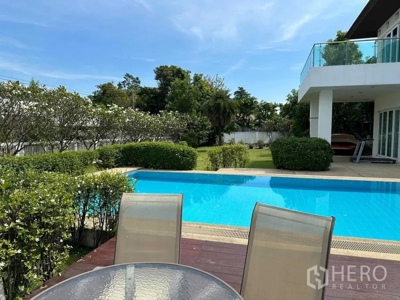 Detached House for rent or sale in Bang Phli, Samut Prakan - Pool deck with glass table and chairs facing lawn and blue pool