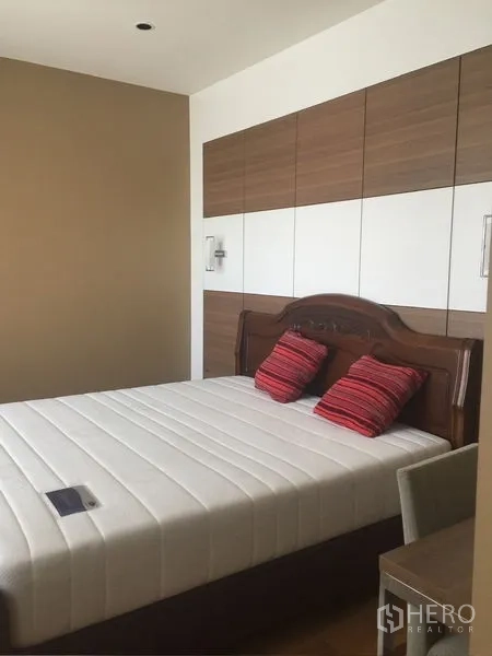 คอนโด ให้เช่า - ห้องนอนที่สองมีผนังหัวเตียงลายไม้ เตียงควีน และหมอนสีแดง