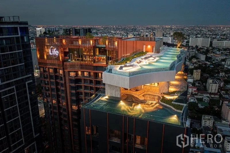 公寓 出售在Chatuchak, Bangkok - 夜景航拍展现点亮的空中泳池与屋顶花园