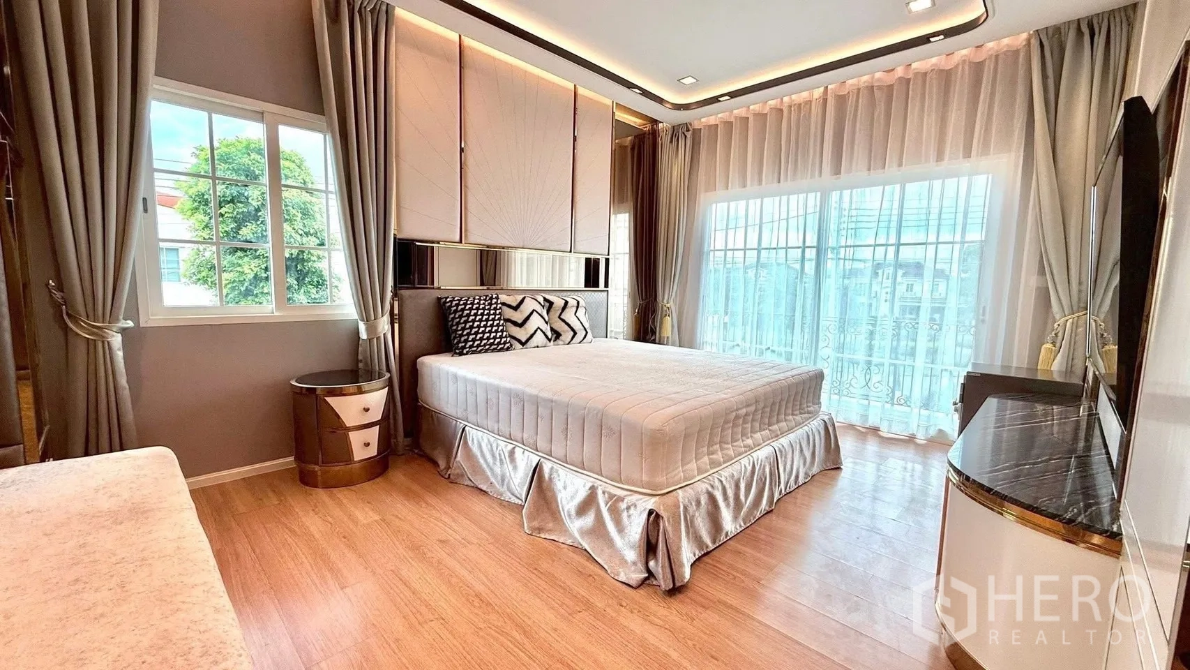 Detached House for rent or sale in Bueng Kum, Bangkok - Master bedroom with king bed, corner windows, sheer drapes and wood flooring.