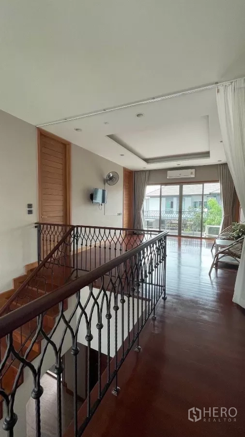 Detached House for rent in Prawet, Bangkok - Upstairs corridor with wrought-iron railing and doors to a balcony.