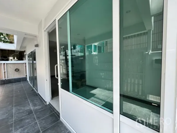 带办公室的家 出租在Watthana, Bangkok - 一层露台，深色地砖与推拉玻璃门相连。