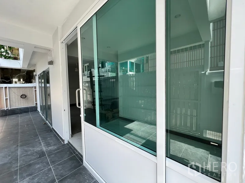 带办公室的家 出租在Watthana, Bangkok - 一层露台，深色地砖与推拉玻璃门相连。