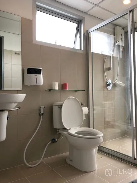 Condominium for rent in Huai Khwang, Bangkok - Modern bathroom with glass-enclosed shower, toilet, vanity, and ventilation window.