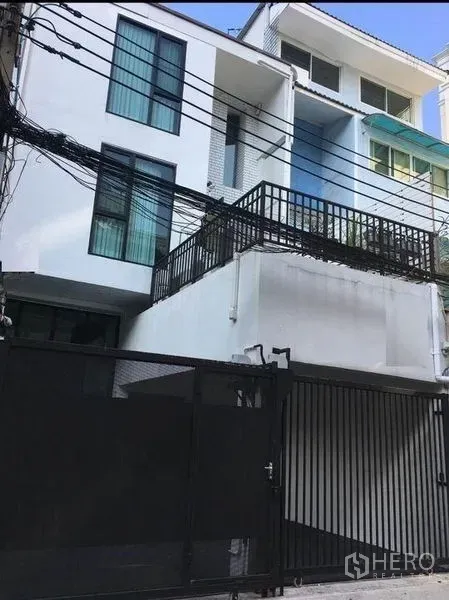 Townhouse for rent in Bang Rak, Bangkok - Contemporary white townhouse façade with balcony and secure gated parking.