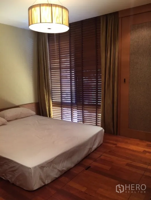 คอนโด ให้เช่าในPathum Wan, Bangkok - ห้องนอนอบอุ่น พื้นไม้ มู่ลี่หน้าต่าง และตู้เสื้อผ้าบิลท์อิน ใต้แสงไฟนุ่มนวล