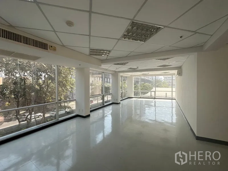 Office Space for rent in Phaya Thai, Bangkok - Bright corner office area with wraparound windows, suspended ceiling lights and tree views.