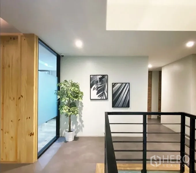 办公空间 出租在Bang Rak, Bangkok - 楼层平台，装饰画、盆栽与栏杆，旁为玻璃墙办公室