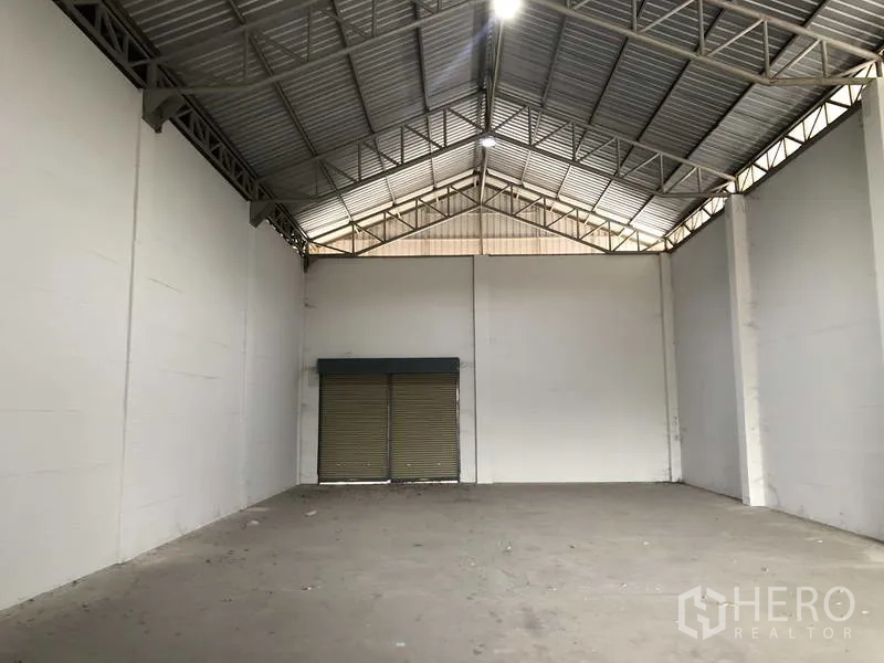 联排别墅 出售在Bang Bua Thong, Nonthaburi - 仓库内部，高挑人字形屋顶与后部卷帘门。