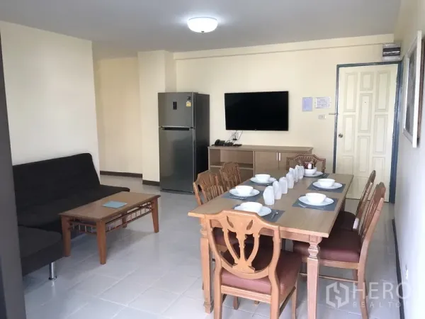Apartment for rent in Suan Luang, Bangkok - Bright living and dining area with a wooden table set, sofa, TV console and stainless refrigerator.