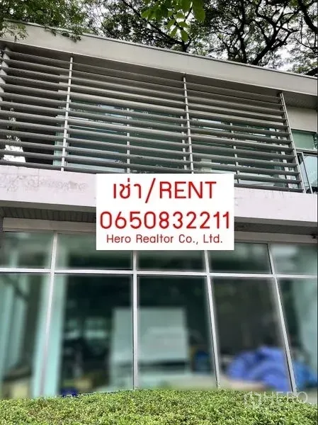 Office Space for rent in Khlong Toei, Bangkok - Modern two‑storey office façade with horizontal sun‑shade louvers and full‑height glass set beneath mature trees, with a rental sign on the front.