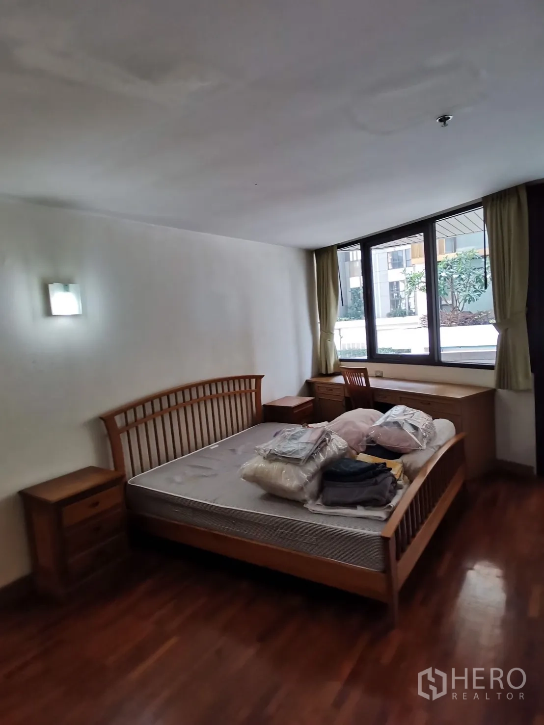 คอนโด ให้เช่าในPathum Wan, Bangkok - ห้องนอนสว่าง เตียงไม้ โต๊ะหัวเตียง และหน้าต่างบานใหญ่หันสู่คอร์ตยาร์ด