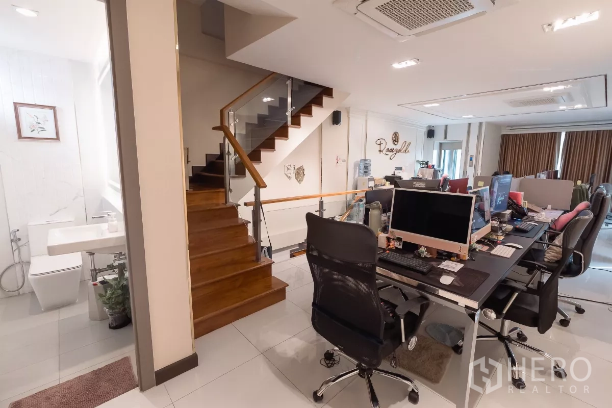 Home Office for sale in Don Mueang, Bangkok - Office level with wooden staircase, shared desks and an adjacent restroom.