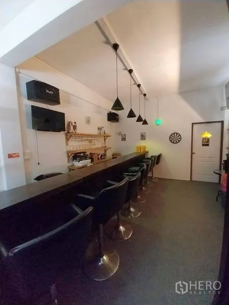 店屋 出租在Khlong Toei, Bangkok - 长吧台配黑色吧椅、吊灯和飞镖靶。