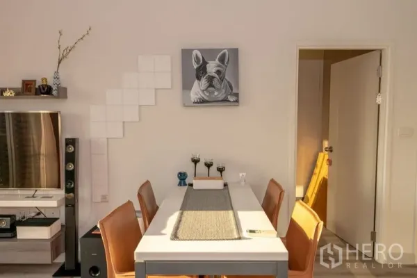 Condominium for rent in Sathon, Bangkok - Dining table for four beside a TV wall unit and decorative shelving.