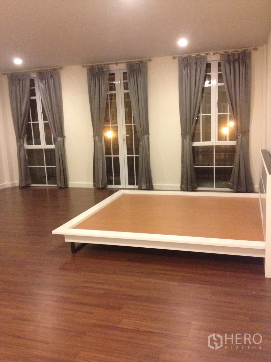 联排别墅 出租在Watthana, Bangkok - 宽敞卧室，木地板、法式落地窗与平台床。