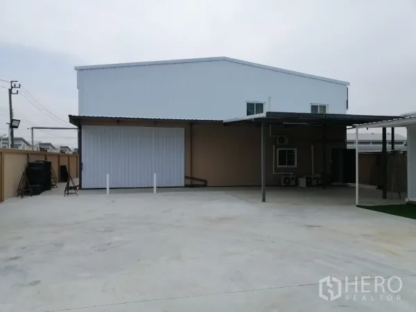 Warehouse for rent in Bang Bua Thong, Nonthaburi - Front yard featuring covered loading bay and oversized roller door to the warehouse.