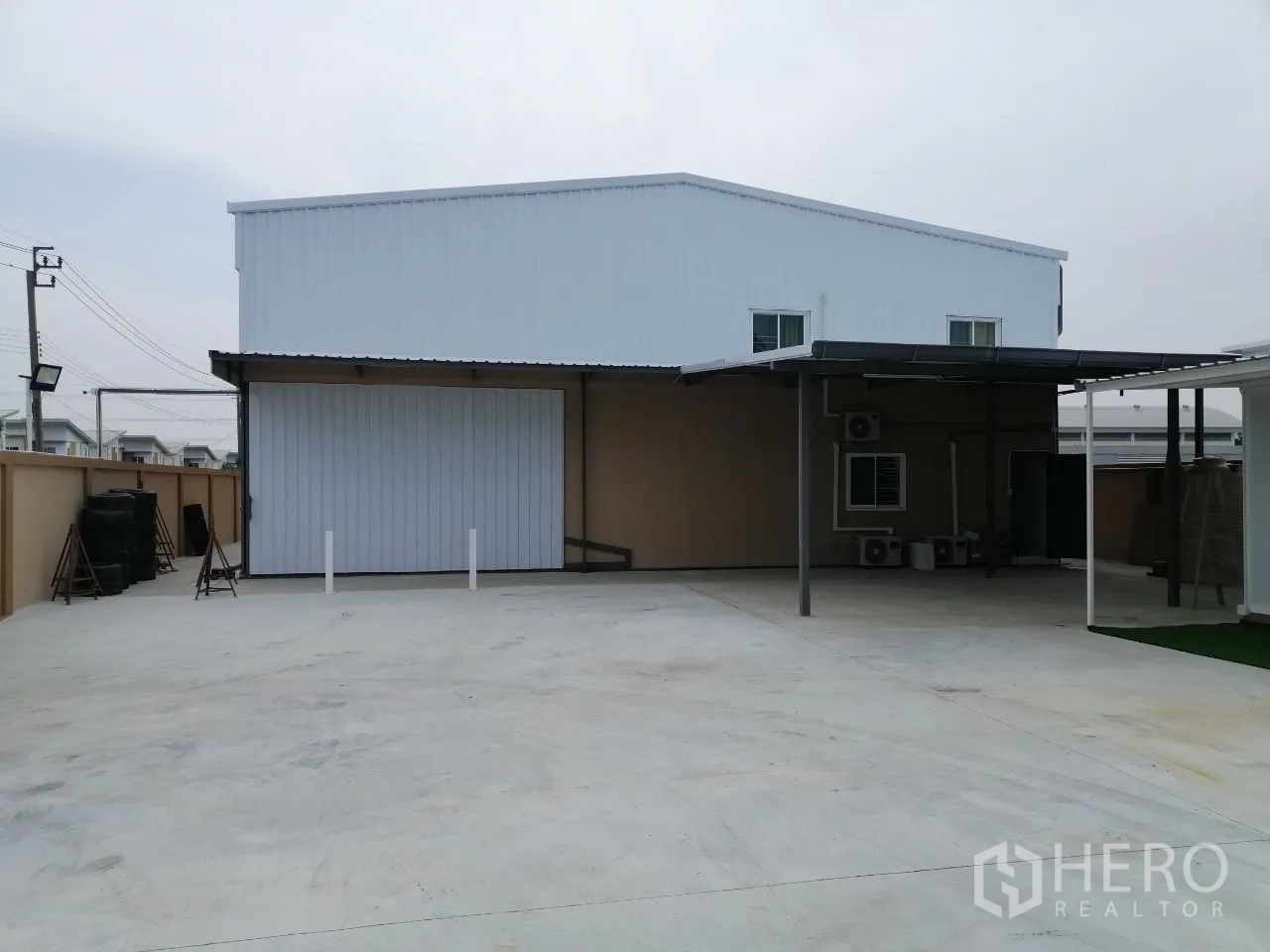 Warehouse for rent in Bang Bua Thong, Nonthaburi - Front yard featuring covered loading bay and oversized roller door to the warehouse.