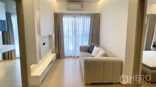 คอนโด ให้เช่าในPhra Khanong, Bangkok - ห้องนั่งเล่นสว่างเฟอร์นิเจอร์โซฟา ผนังกระจกสูงเปิดออกสู่ระเบียงและชั้นวางทีวีบิวท์อิน