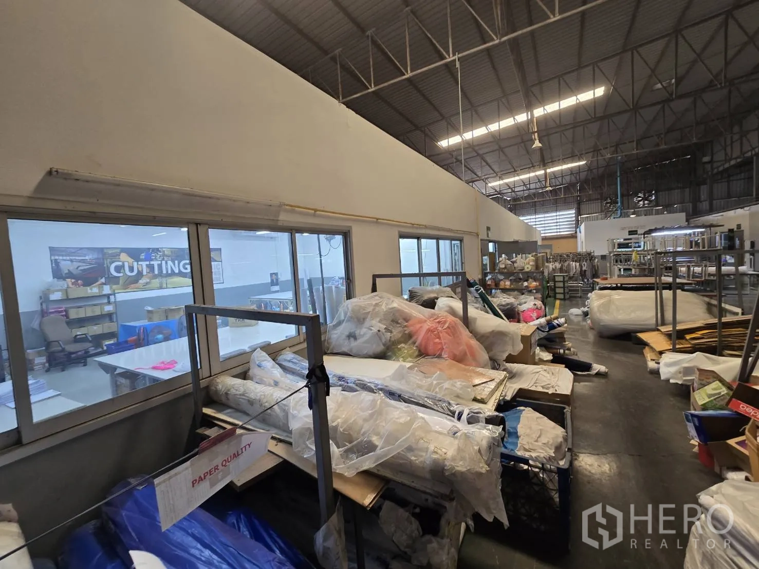 Factory for rent in Sam Phran, Nakhon Pathom - Partitioned rooms with large windows beside storage aisles of materials.