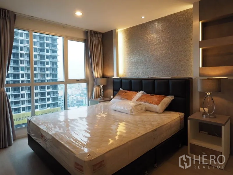 Condominium for rent in Sathon, Bangkok - Master bedroom with upholstered headboard, bedside tables and panoramic city views.