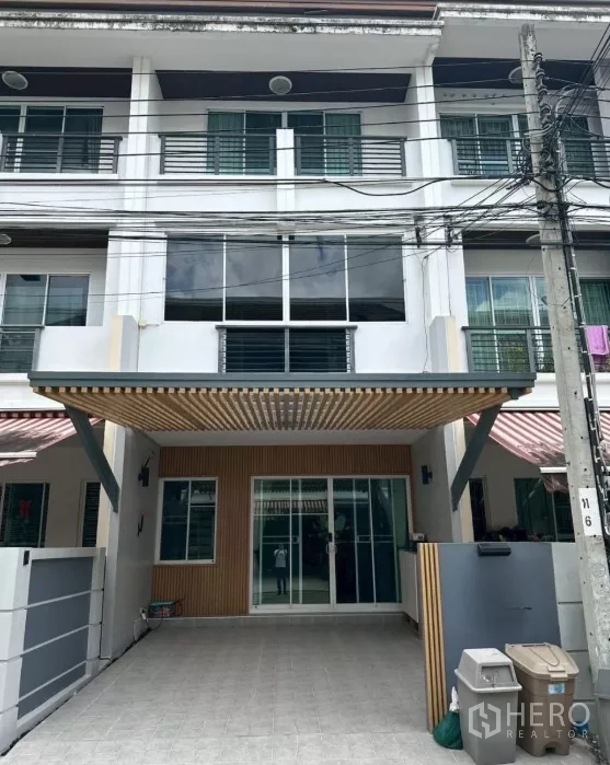 Townhouse for rent in Chom Thong, Bangkok - Three-storey townhouse facade with covered carport and sliding glass entrance.