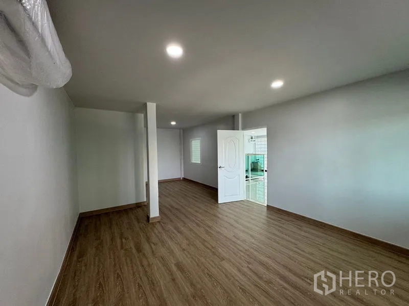 Home Office for rent in Bueng Kum, Bangkok - Long wood-floor room with door to tiled bathroom and a glass-block window.