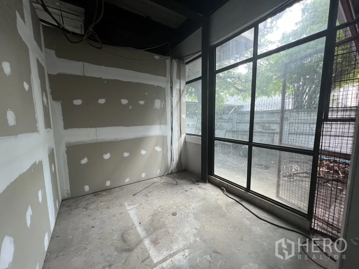 พื้นที่ขายปลีก ให้เช่าในWatthana, Bangkok - ห้องกั้นผนังยิปซัมยังไม่เสร็จ พร้อมหน้าต่างบานใหญ่ติดรั้วและต้นไม้