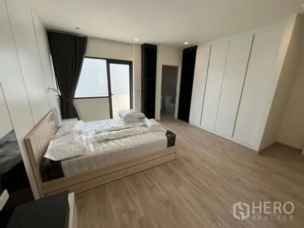 Townhouse for rent or sale in Don Mueang, Bangkok - Spacious bedroom with built-in wardrobes, en-suite bathroom and wood floors.