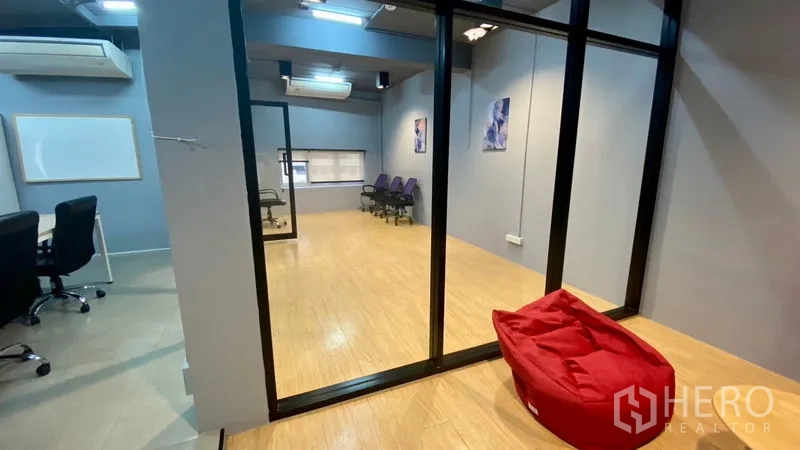 办公空间 出租在Sathon, Bangkok - 玻璃墙房间连接到明亮的多功能空间，木地板与座椅齐备。