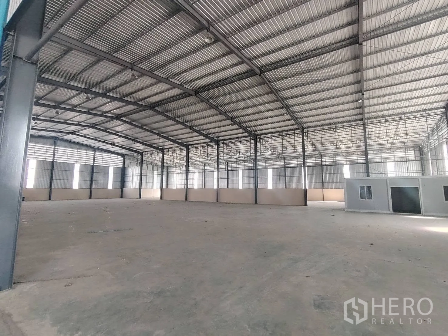 Warehouse for rent in Bang Phli, Samut Prakan - Open-plan warehouse interior with high steel roof, concrete floor, and a small internal office unit.