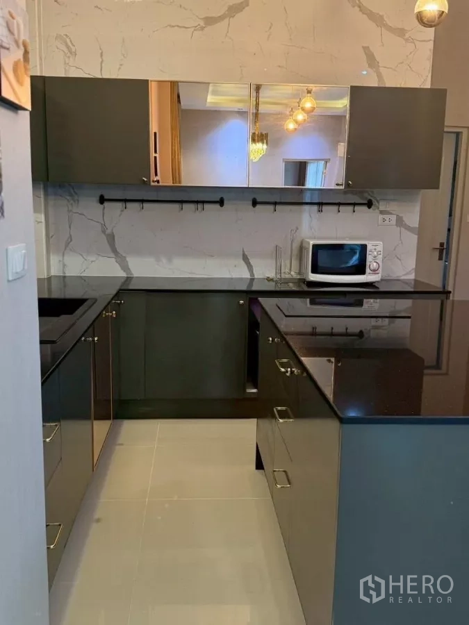 Detached House for rent or sale in Bang Phli, Samut Prakan - Stylish U‑shaped kitchen with glossy black countertops, marble backsplash and upper cabinets.