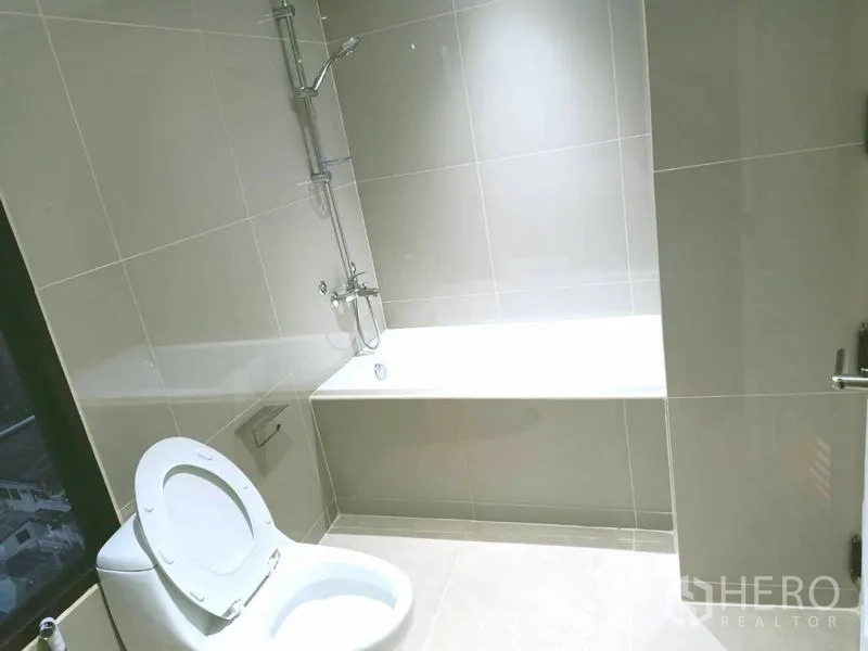 Condominium for  in Watthana, Bangkok - Bright bathroom with bathtub, shower and light gray tiles.
