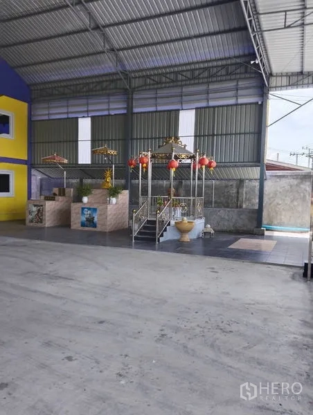 Warehouse for sale in Sai Noi, Nonthaburi - Tiled area with a decorative pavilion and steps beside the warehouse wall.