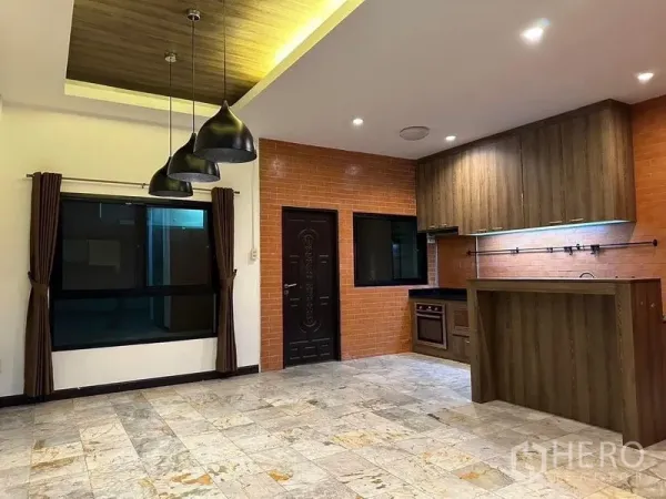 Townhouse for rent in Phaya Thai, Bangkok - Open-plan kitchen with brick backsplash, wood cabinetry, island counter and black pendant lights.
