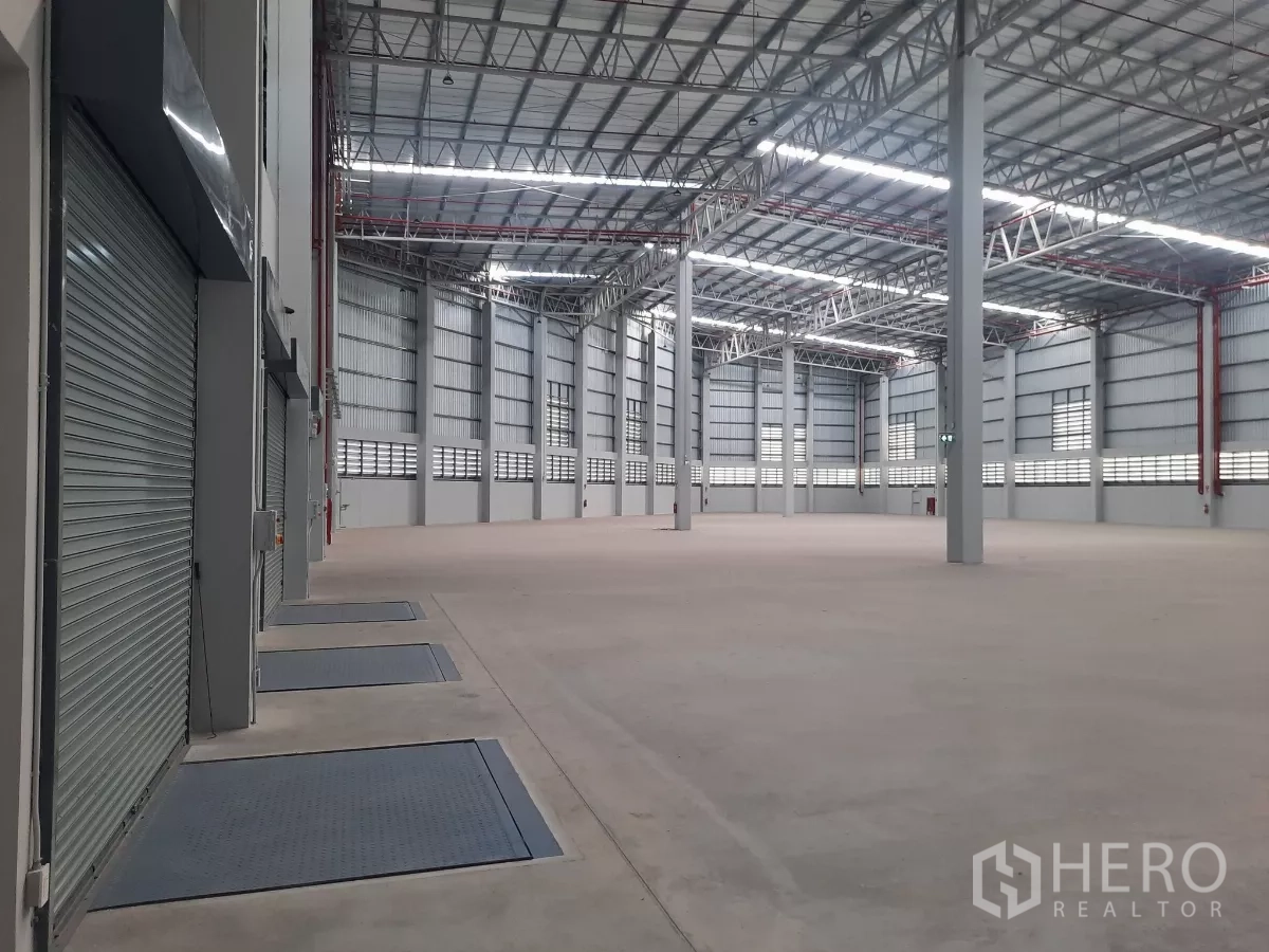 Factory for rent in Bang Lamung, Chon Buri - Interior view of dock levelers and roller shutters along a service wall.