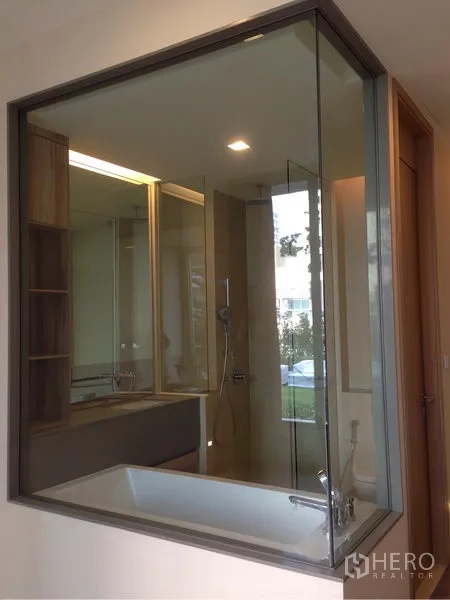 Condominium for rent or sale in Watthana, Bangkok - Glass-walled bathroom featuring a soaking tub and separate shower with built-in shelving