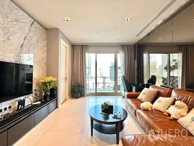 Condominium for rent in Pathum Wan, Bangkok - Bright living room with marble feature wall, leather sofa, TV console and balcony city view.