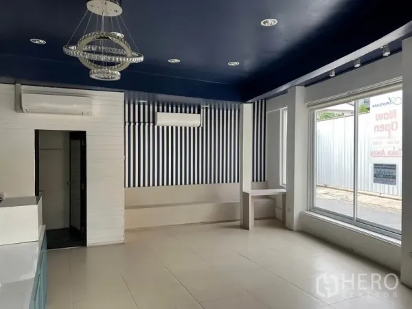 零售空间 出租在Watthana, Bangkok - 店内明亮空间，瓷砖地面、海军蓝天花、条纹墙面与大窗采光。