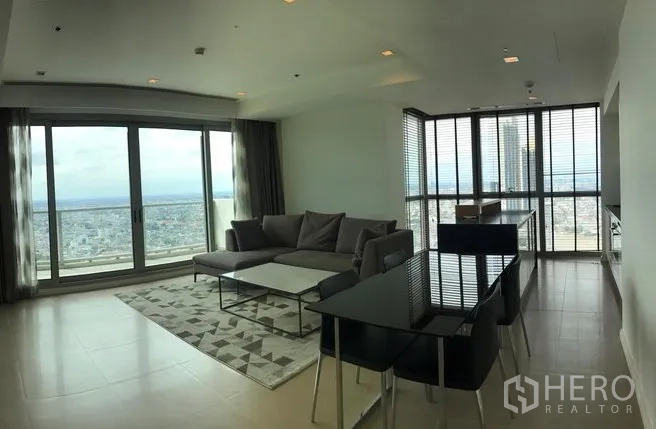 Condominium for rent or sale in Khlong San, Bangkok - Open-plan living and dining area with large windows and sweeping city views.