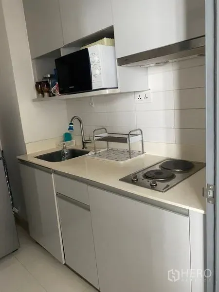 公寓 出售在Phra Khanong, Bangkok - 简洁白色小厨房，含水槽、电炉、抽油烟机与微波炉
