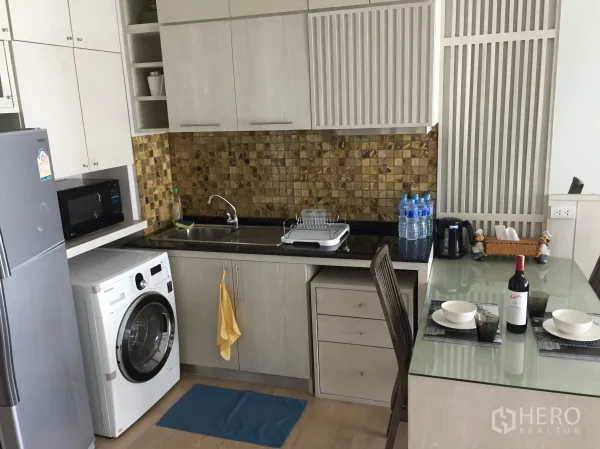 公寓 出租在Bangkok - 现代厨房，马赛克墙面，水槽、微波炉、冰箱、洗衣机与玻璃餐桌。