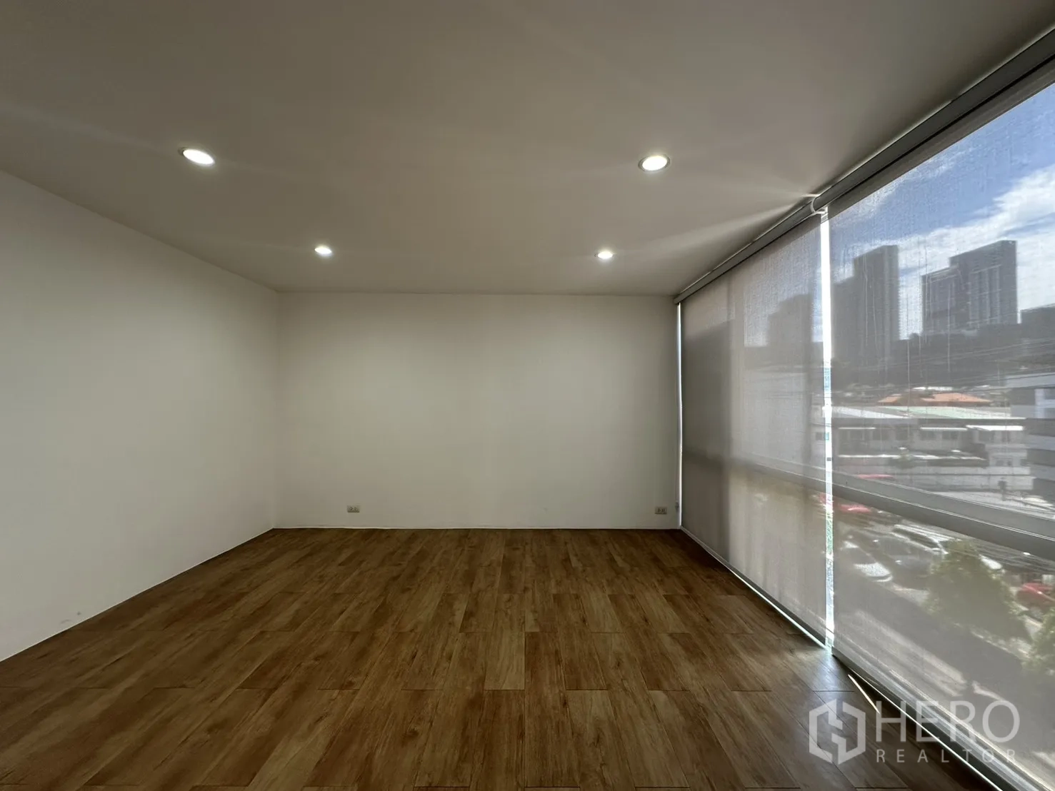 Home Office for rent in Phra Khanong, Bangkok - Large workspace with wood floors and full-height windows with blinds.