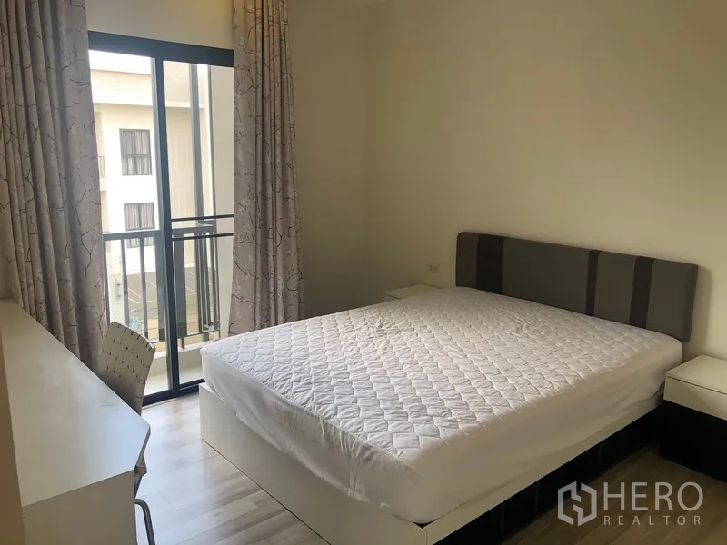 Townhouse for rent in Saphan Sung, Bangkok - Guest bedroom with queen bed, work desk and sliding doors opening to a small balcony.