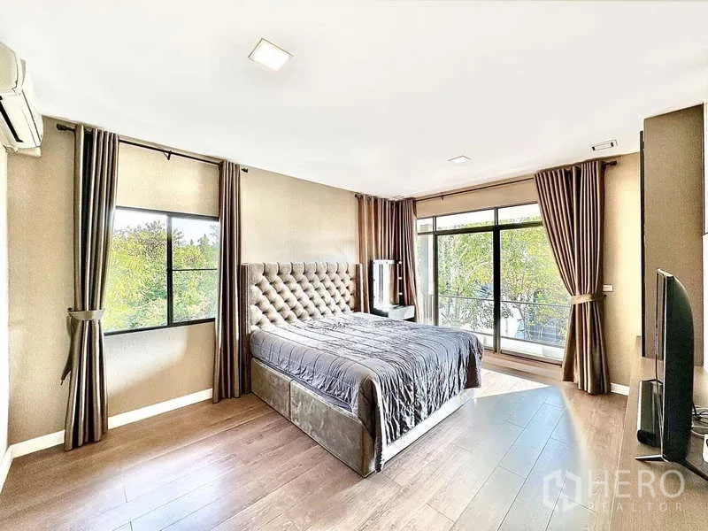 Detached House for sale in Bang Phli, Samut Prakan - Spacious master bedroom with tufted headboard, large windows and sliding doors to a balcony.