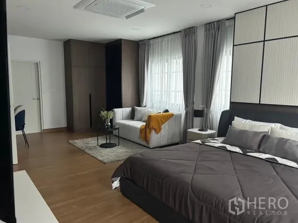 Detached House for rent or sale in Bang Phli, Samut Prakan - Spacious master bedroom with king bed, sofa sitting area, wood floors and large windows.