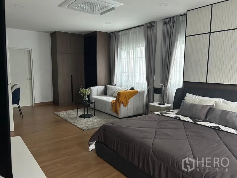 Detached House for rent or sale in Bang Phli, Samut Prakan - Spacious master bedroom with king bed, sofa sitting area, wood floors and large windows.